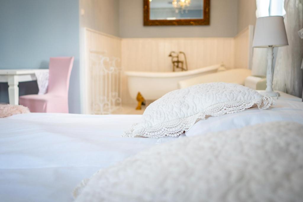 a bedroom with a white bed and a bath tub at Gyula Panzio in Gyula