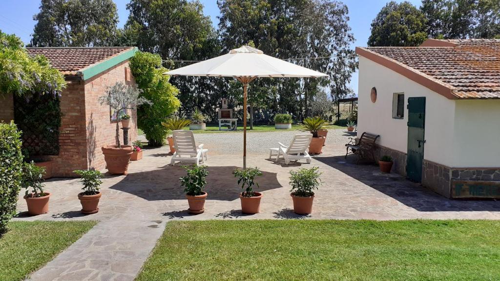 eine Terrasse mit Stühlen und einem Sonnenschirm im Hof in der Unterkunft Agriturismo Prato Verde in Principina a Mare