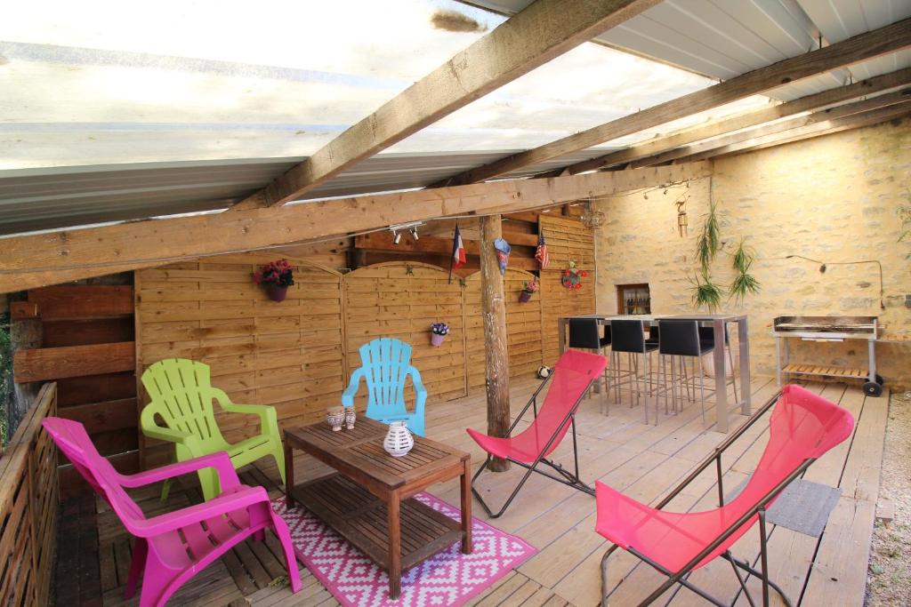 a patio with colorful chairs and a table on a deck at La ferme aux chats in Formigny