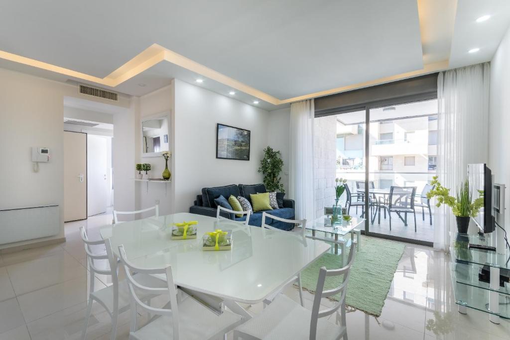 ein weißes Esszimmer und ein Wohnzimmer mit einem weißen Tisch und Stühlen in der Unterkunft Full Option 7 people in Jerusalem