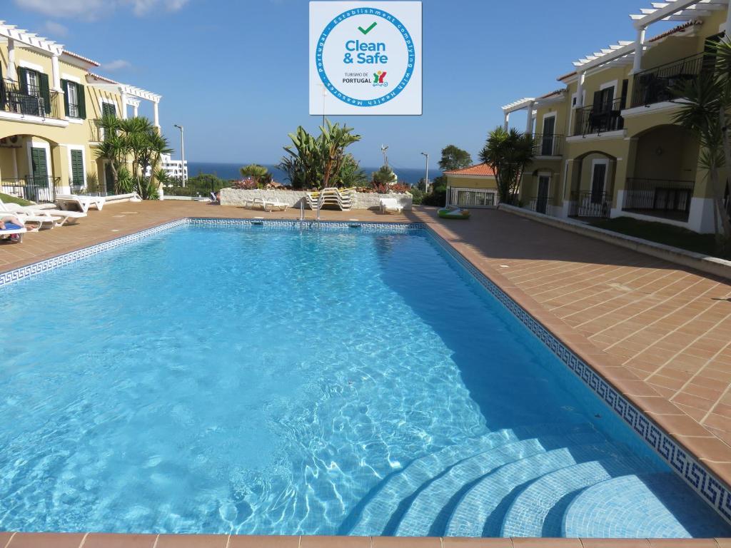 una piscina de agua azul frente a algunos edificios en Apartamento T1 com vista mar perto da Praia N.ª Sra. da Rocha, en Porches