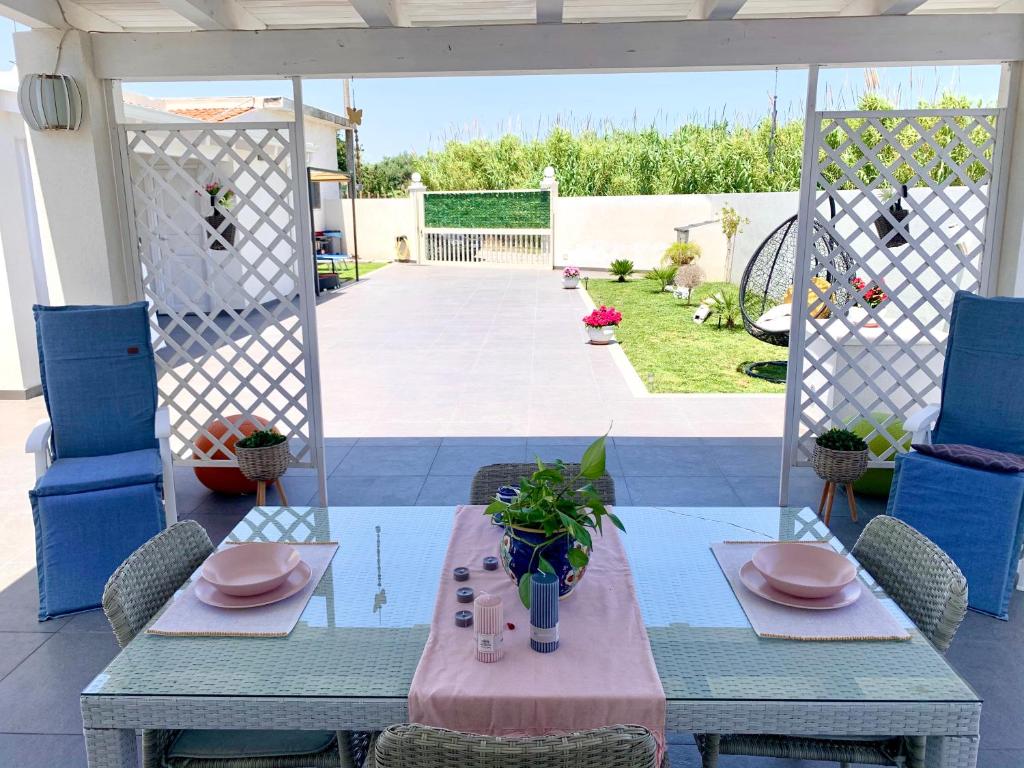 einen Tisch und Stühle auf einer Terrasse mit einem Tisch und einem sidx sidx in der Unterkunft Villa White Sicilia in Santa Maria Del Focallo