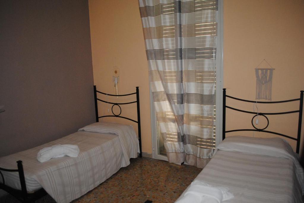 two twin beds in a room with curtains at Summer Beach Rooms in Fontane Bianche
