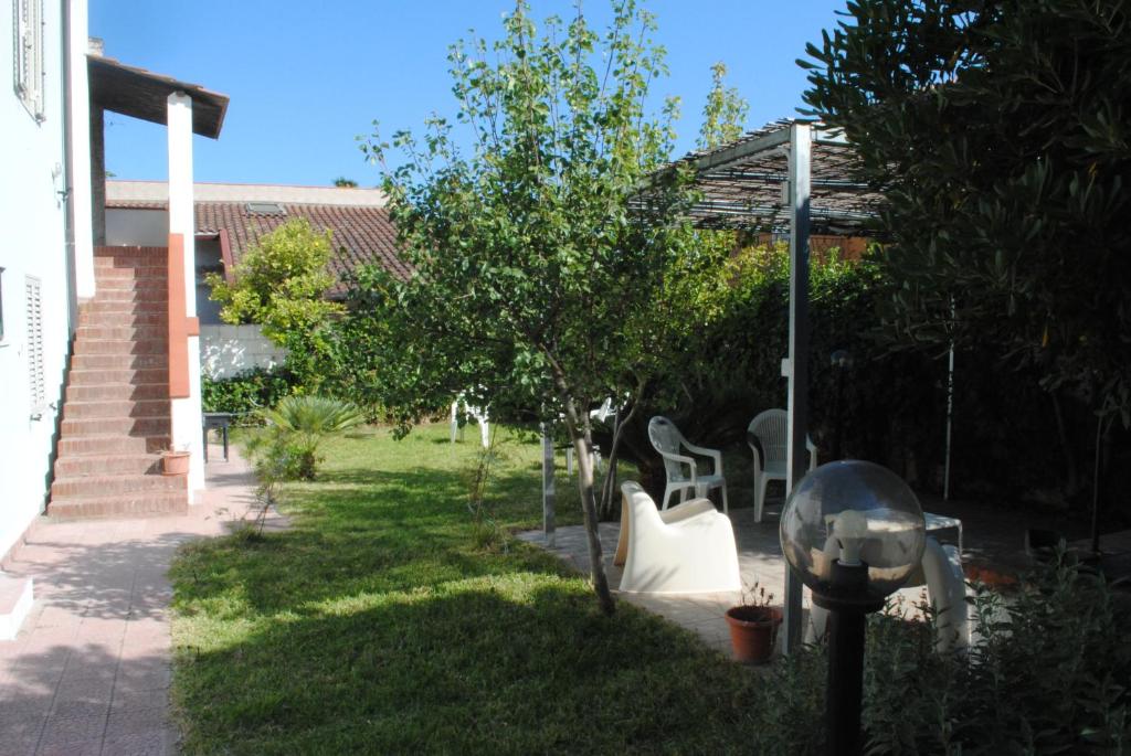a garden with a tree and chairs and a lamp at Summer Beach Rooms in Fontane Bianche