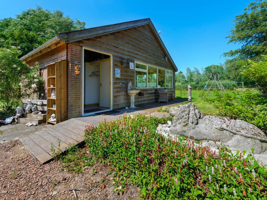 a small wooden cabin with a wooden deck in a yard at Enticing Holiday Home in Eastermar near Burgumer Mar Lake in Hoogzand