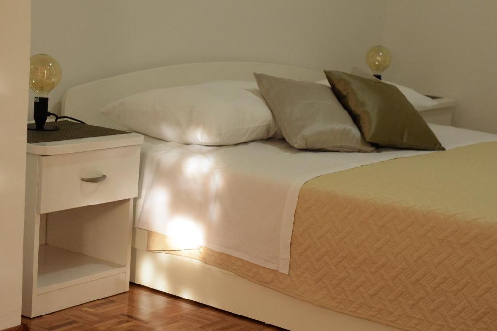 Studio apartman MARINA في فوديس: سرير أبيض مع منضدة بيضاء وسرير أبيض sidx