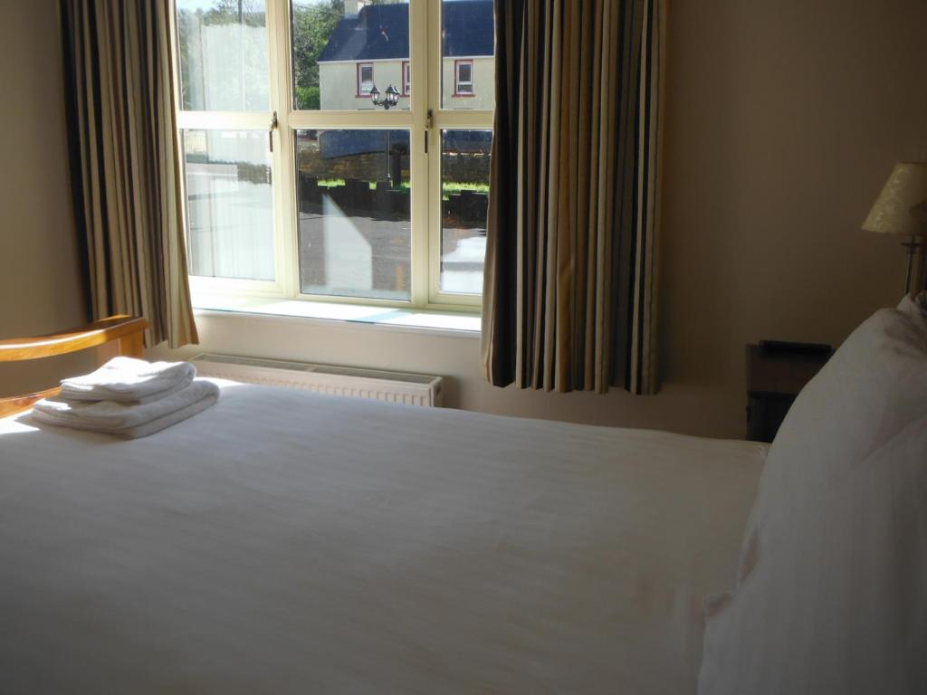 a bedroom with a white bed and a window at Inspiration Lodge in Anascaul
