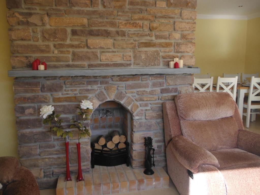 a living room with a brick fireplace with a chair at Inspiration Lodge in Anascaul