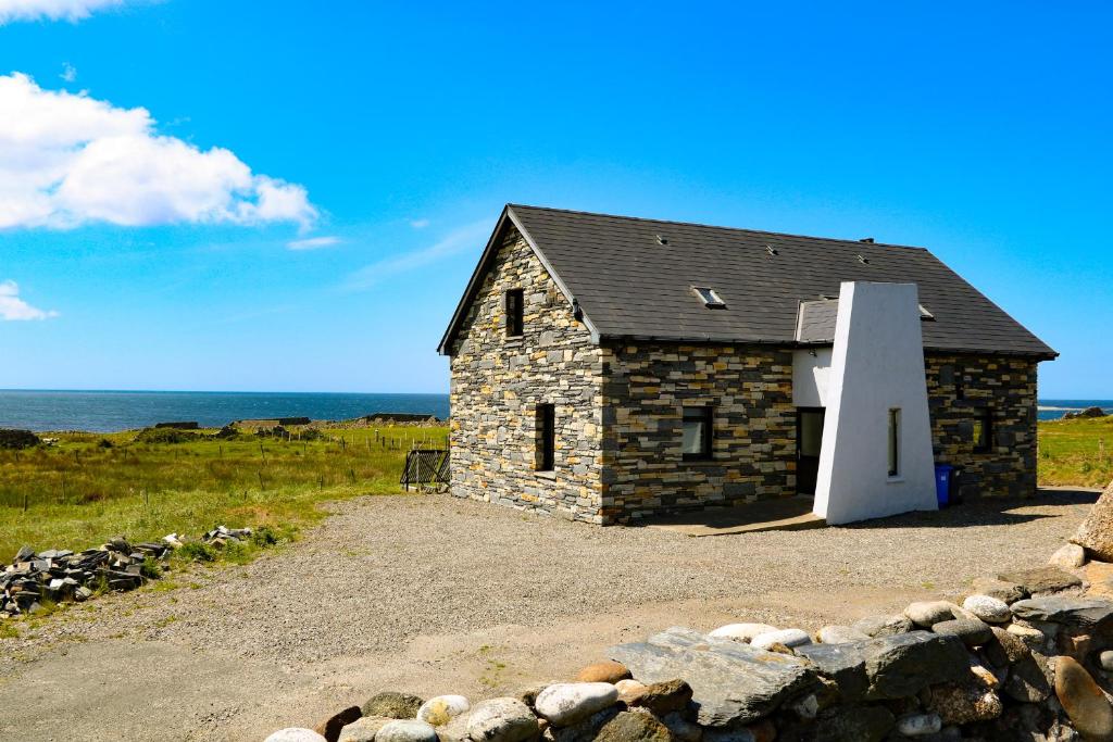 a small stone house on the side of the ocean at Ocean Sail House in Dungloe