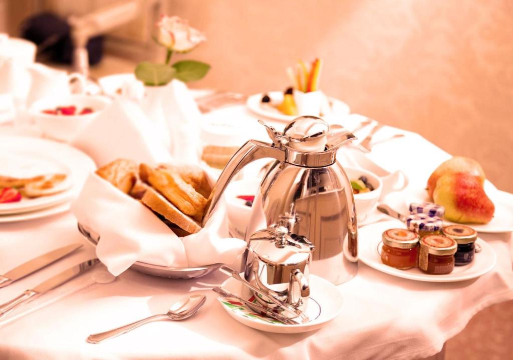 A formal breakfast table set with coffee service, pastries, fruit, and preserves.