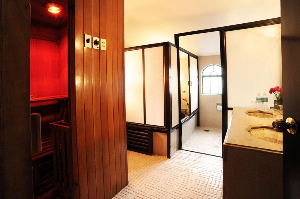 A bathroom with a double vanity, walk-in shower area, and a separate wood-paneled sauna.