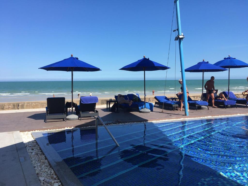 a swimming pool with umbrellas and people on the beach at Amari Residence in Khao Tao