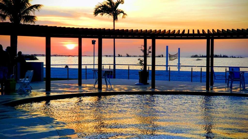 uma piscina com um pôr-do-sol ao fundo em O paraíso é aqui - Golden Lake em Arraial do Cabo