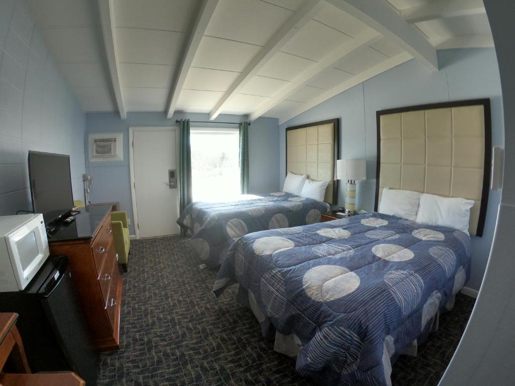 a hotel room with two beds and a television at Copper Lantern Motor Lodge in West Brookfield