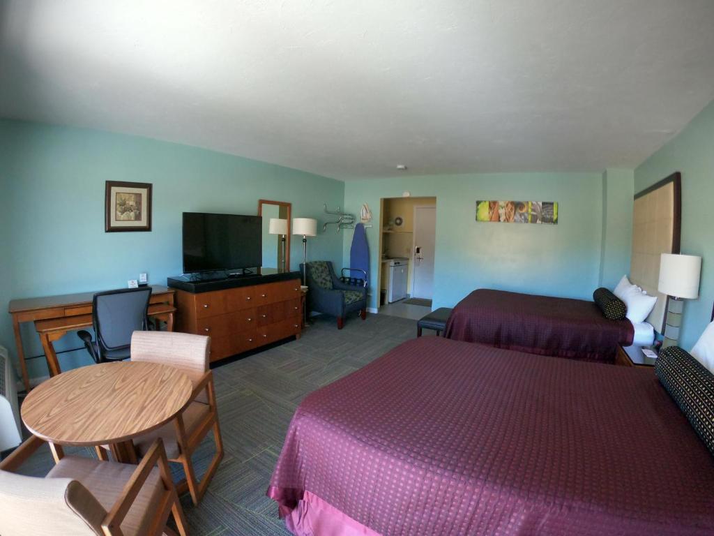a hotel room with two beds and a table at Copper Lantern Motor Lodge in West Brookfield