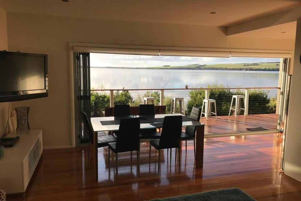 a dining room with a table and chairs and a balcony at Amazing Ansons Bay Absolute Waterfront Beach House in Ansons Bay