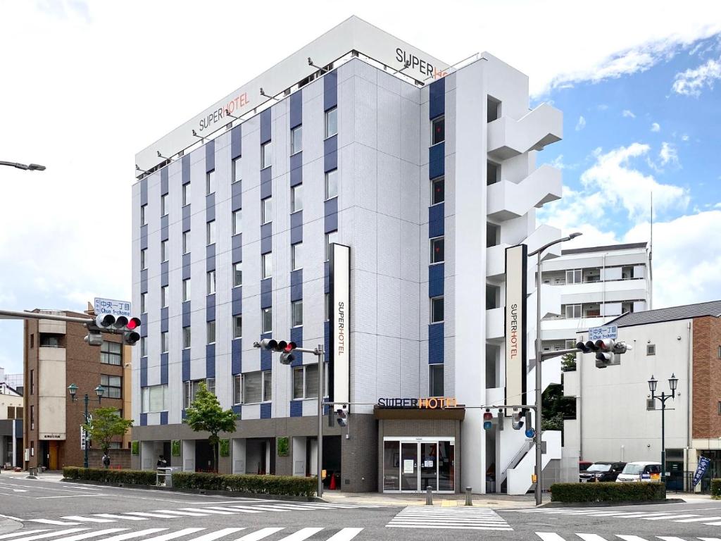 a white building with blue windows on a street at Super Hotel Matsumoto Ekimae in Matsumoto