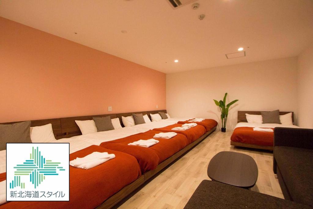 a hotel room with three beds with orange sheets at SEVEN Building / Vacation STAY 4946 in Asahikawa