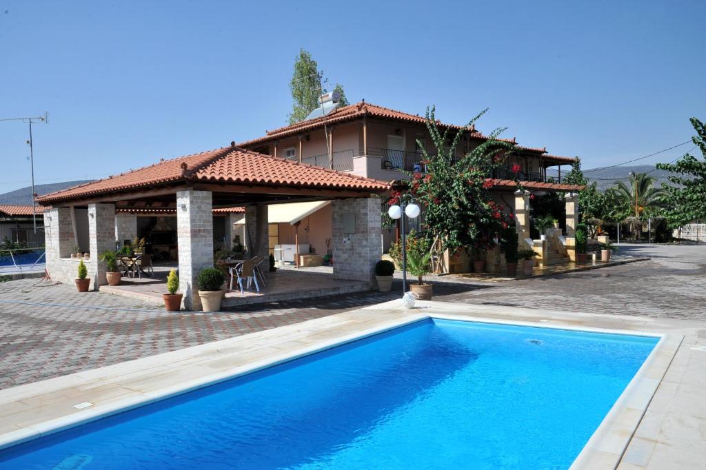 a swimming pool in front of a house at Angelos Κandia Apartments in Kandia