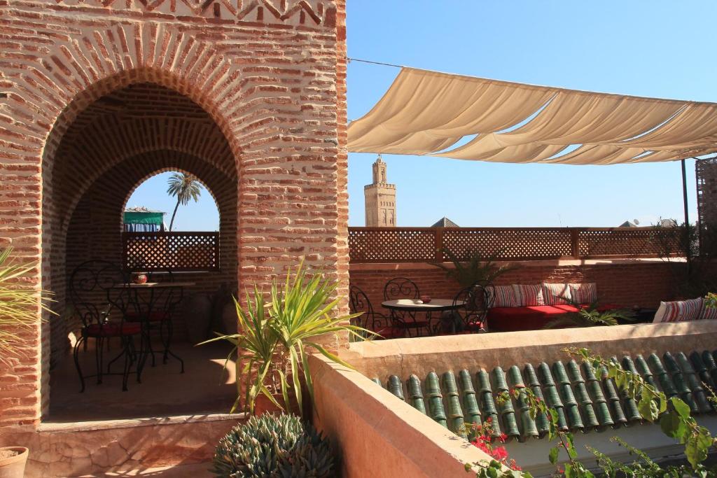 eine Außenterrasse mit 2 Bögen, Tischen und Stühlen in der Unterkunft Riad Samsara in Marrakesch