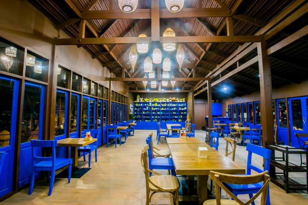 a restaurant with blue chairs and tables and wine racks at Rachawadee Resort & Hotel in Khon Kaen