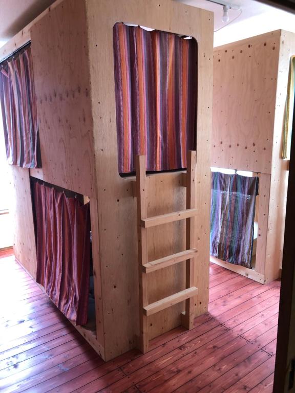 una cabina con tre finestre in una camera con pavimenti in legno di 尾道ゲストハウス シータ村 a Onomichi