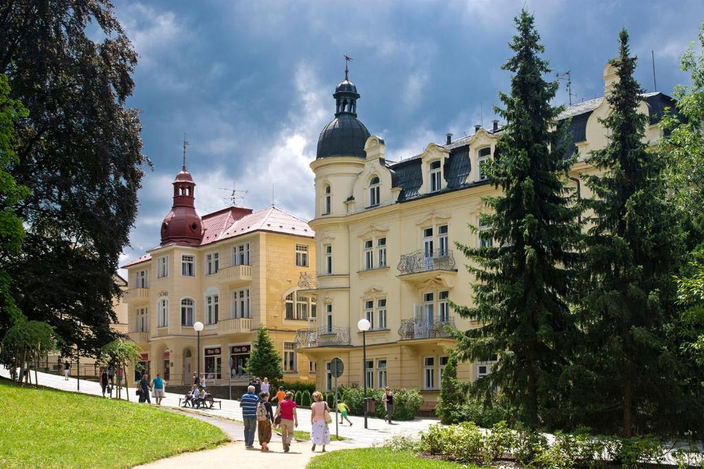 un grand bâtiment avec des personnes qui marchent devant lui dans l'établissement Villa Dagmar, à Luhačovice