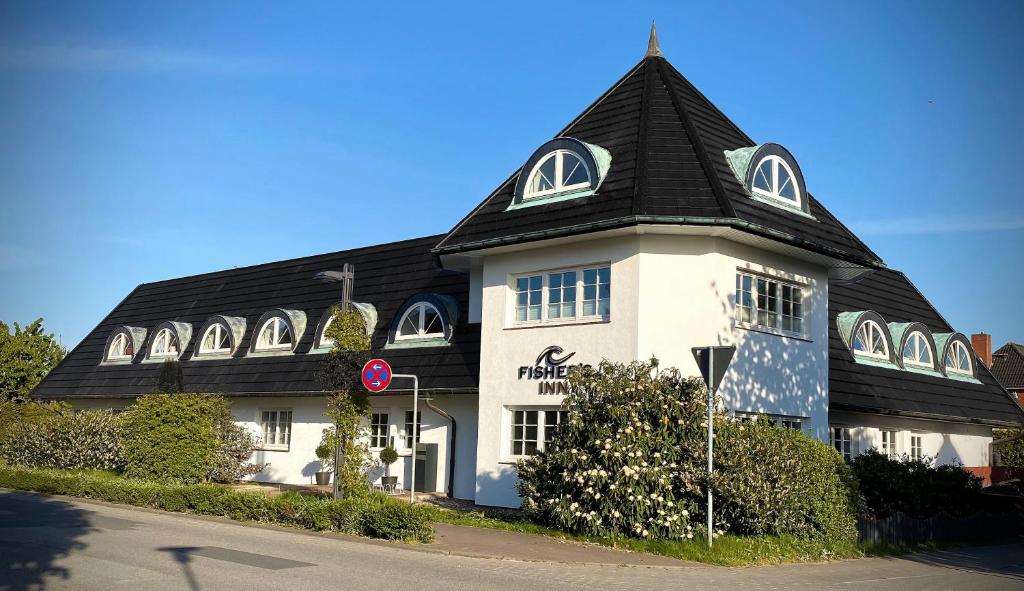 un grand bâtiment blanc avec un toit noir dans l'établissement Fisher's Inn, à Zingst