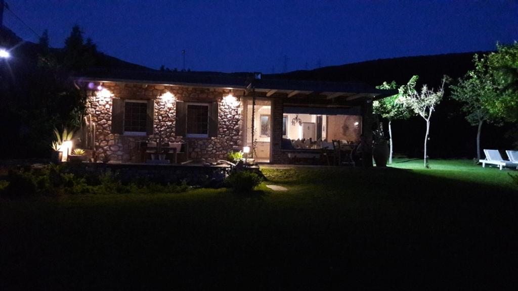 una casa de piedra por la noche con luces encendidas en Klovino beach house, en Douviá