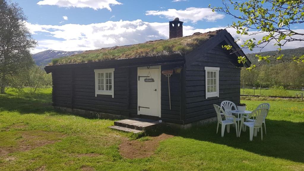 una pequeña casa con techo de hierba, mesa y sillas en Gammelstuggu, en Bjorli