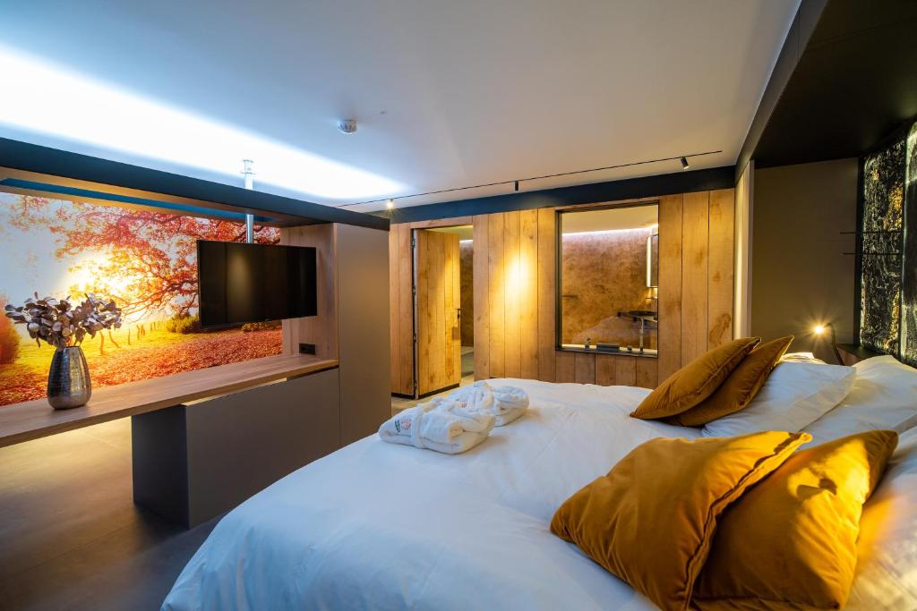 een slaapkamer met een groot bed en een flatscreen-tv bij L'Ardenne Autrement in La-Roche-en-Ardenne