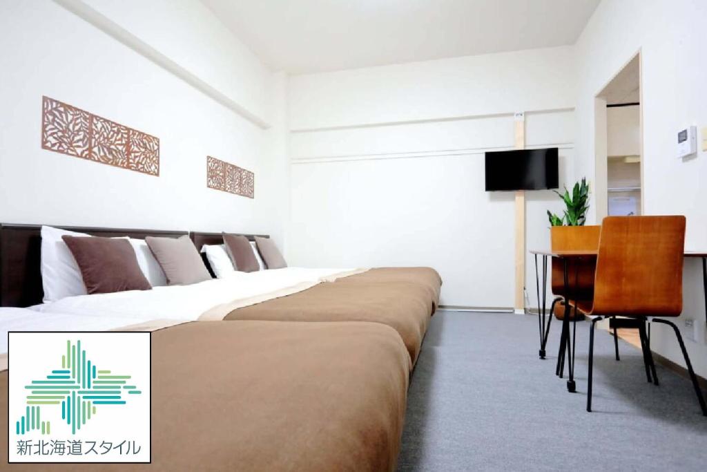 ein Hotelzimmer mit 2 Betten und einem Schreibtisch in der Unterkunft Mansion Pasture TSUKISAMU Fukuzumi in Sapporo