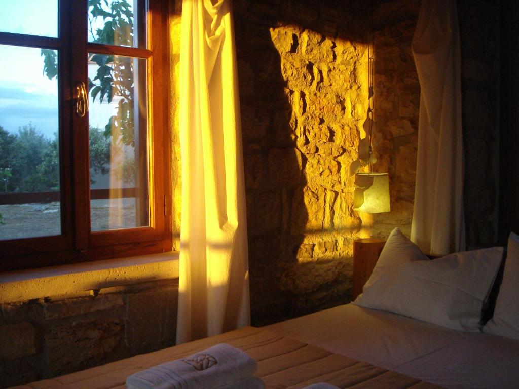 a bedroom with a bed with a window and a lamp at Kastraki Art Houses in Kousounárion