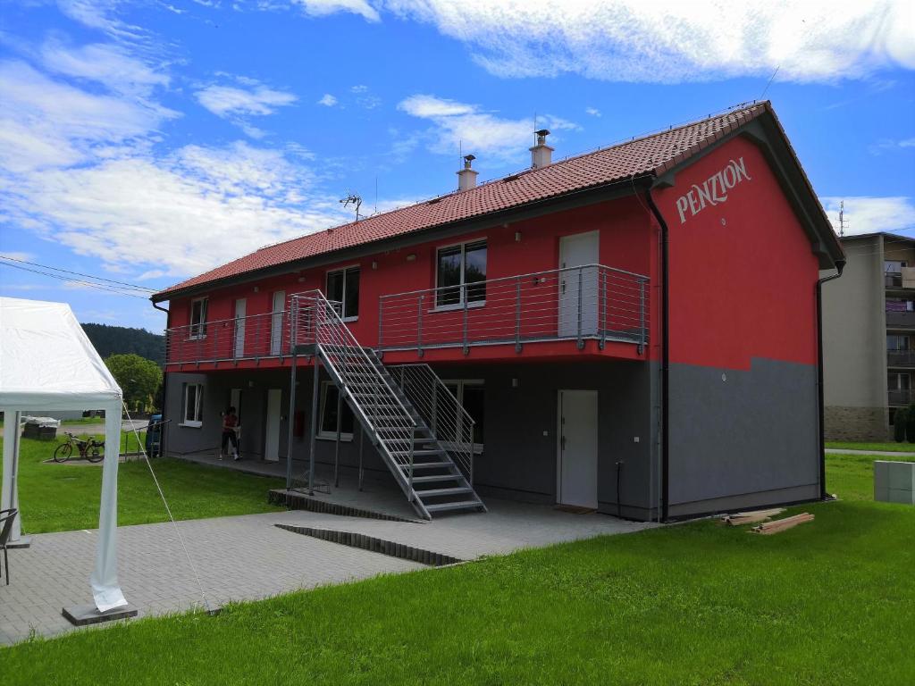 a red building with a staircase on the side of it at Penzion Sloup in Sloup
