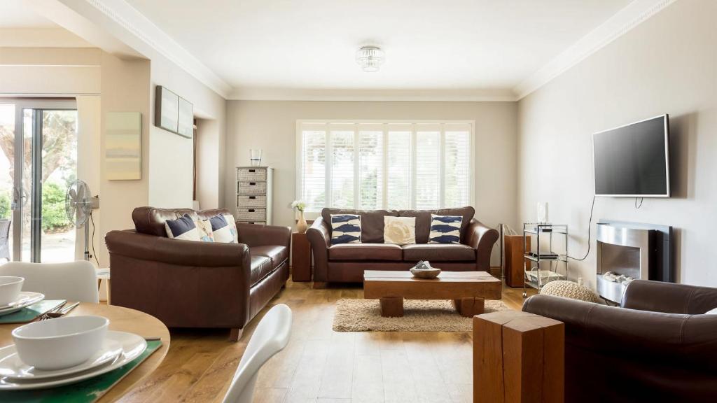 uma sala de estar com mobiliário de couro e uma televisão em Sandy Shores - Sandbanks em Poole