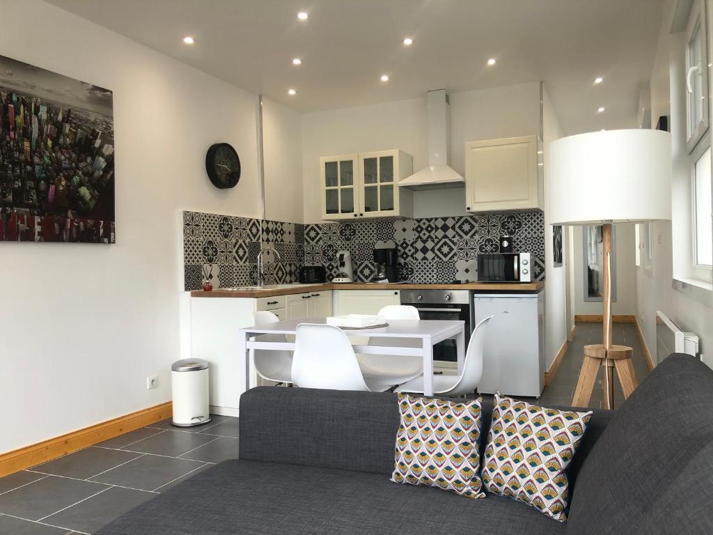 een woonkamer met een bank en een keuken bij Appartement avec jardin in Isbergues