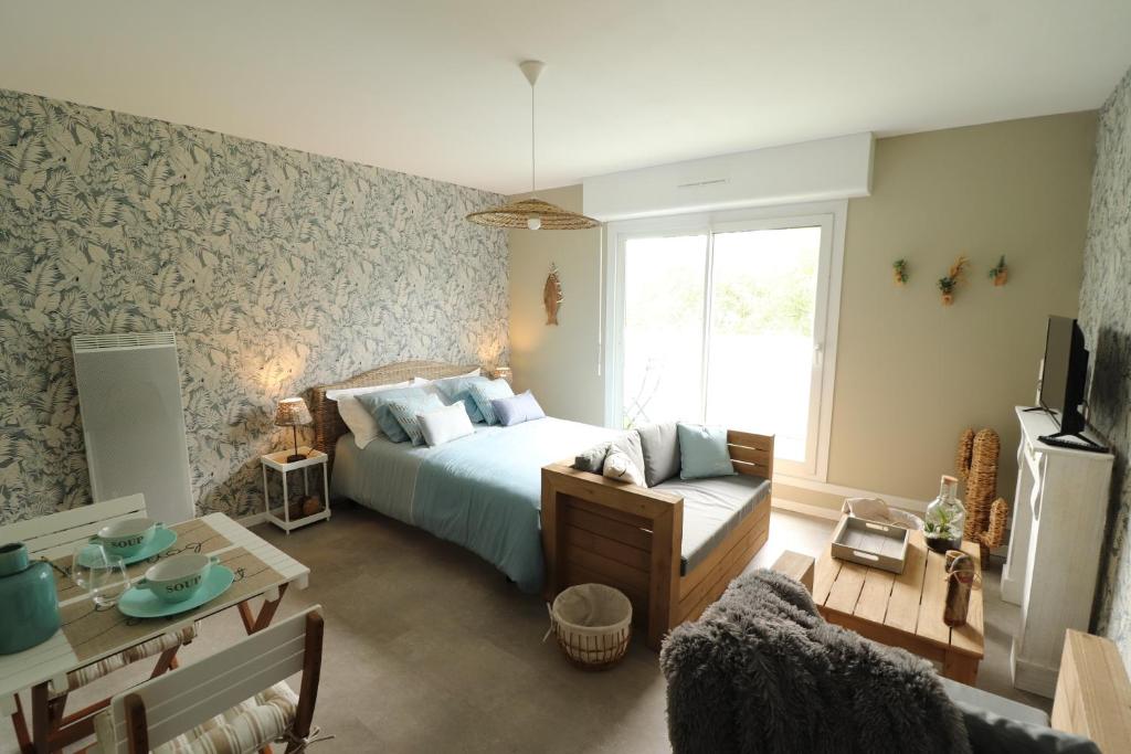 1 dormitorio con cama, sofá y mesa en Les Platanes en Saint-Lô