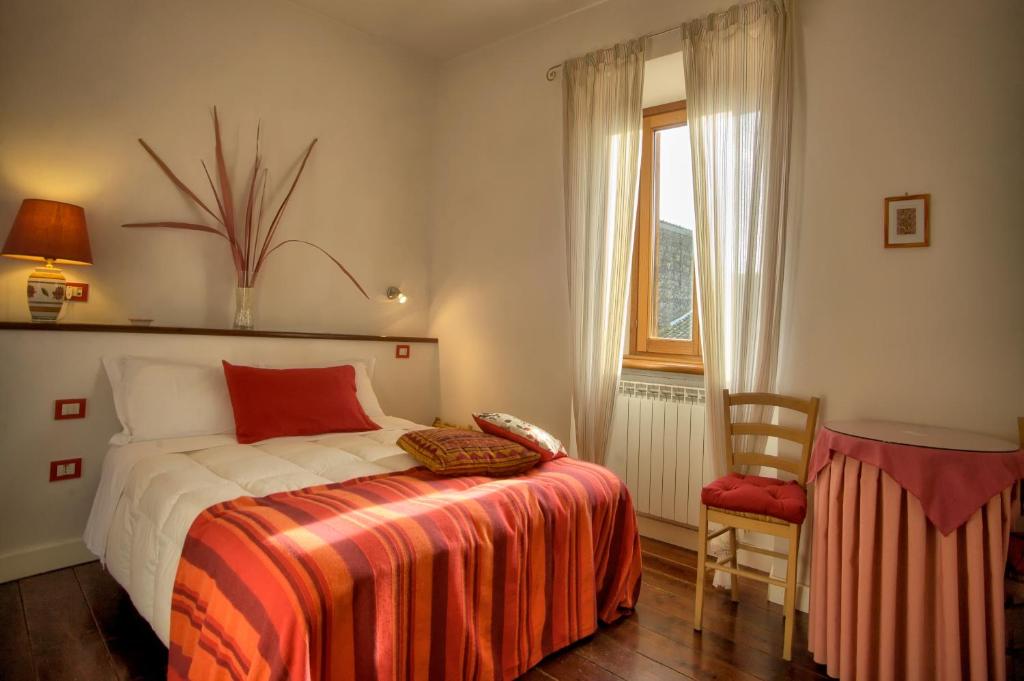 1 dormitorio con 1 cama, 1 silla y 1 ventana en La Torretta, en Tuscania