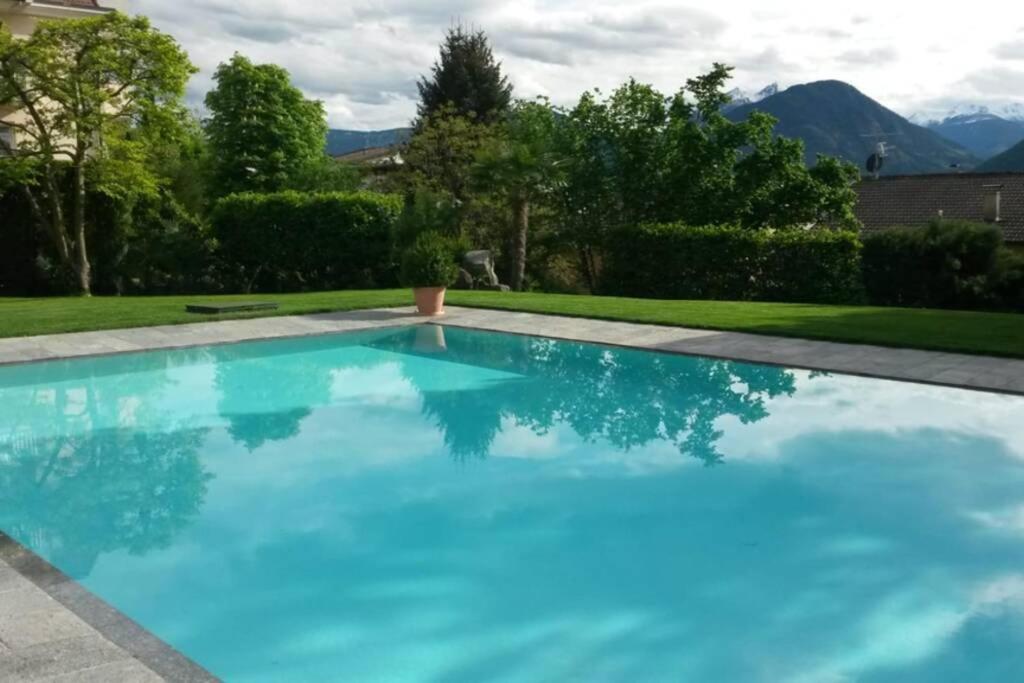 een zwembad met blauw water in een achtertuin bij Appartement Pienzenau in Merano