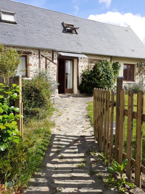 una antigua casa de piedra con una valla de madera en Le gite du hibou, en Ménil-Hubert-sur-Orne