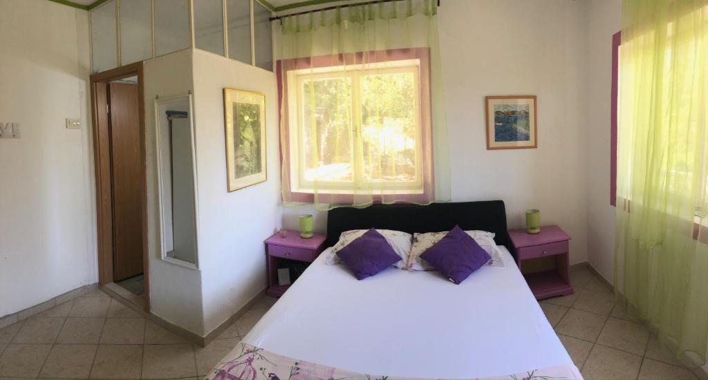 - une chambre avec un lit blanc et des oreillers violets dans l'établissement Family Stakic, à Baška Voda