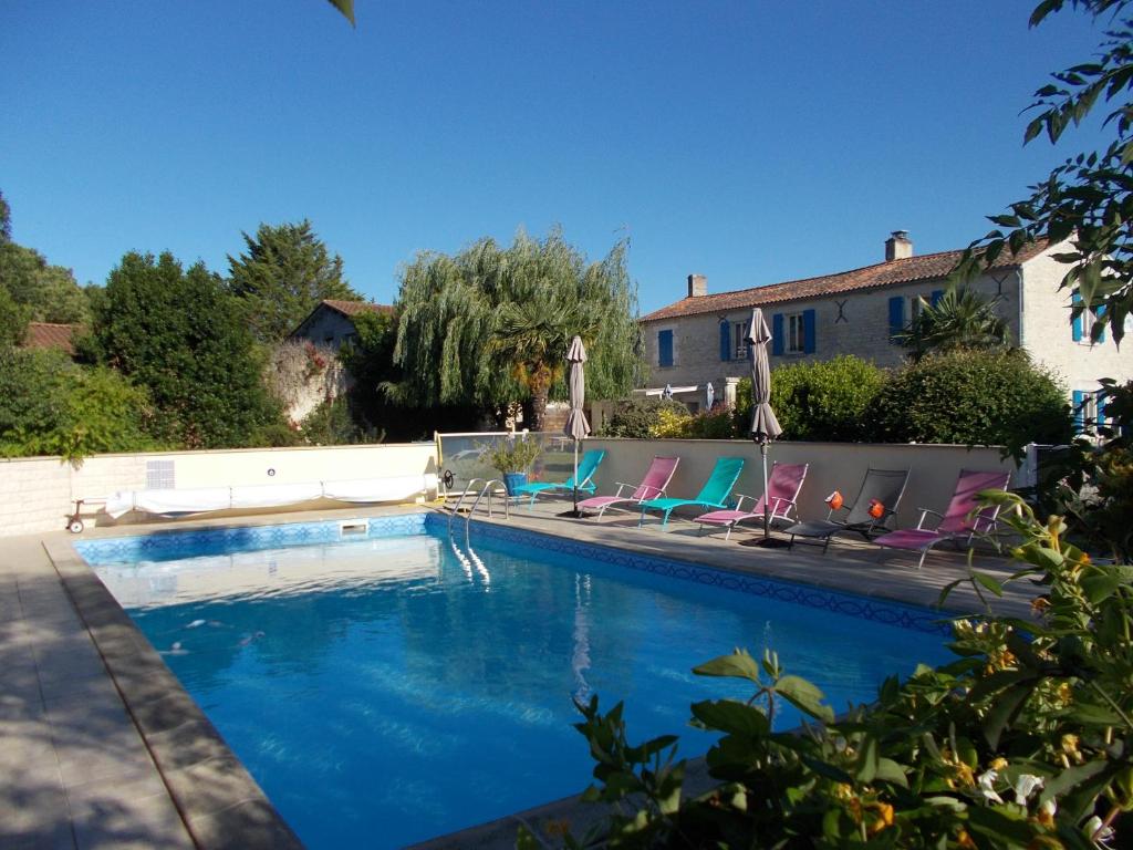 a swimming pool with chairs and a house at Le Clos des Palmiers in Saint-ouen-dʼAunis