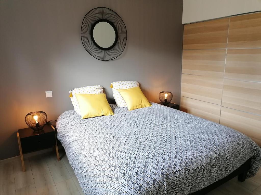 una camera da letto con letto, cuscini gialli e specchio di Les gîtes aux portes de Saint-Quay-Portrieux a Plourhan