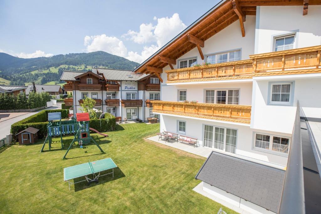 un gran patio con parque infantil frente a un edificio en Aparthotel Pichler en Flachau