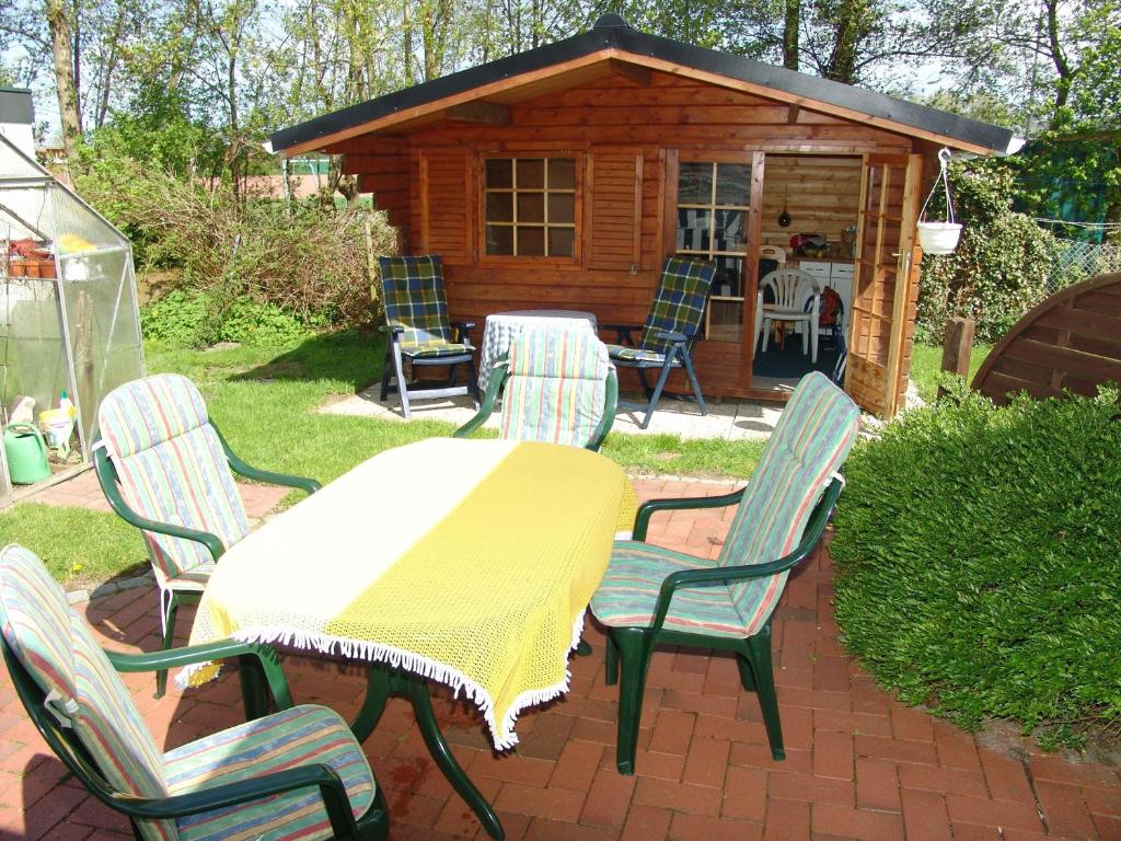 un patio con mesa y sillas y una cabaña en Haus-Norderpiep, en Büsum
