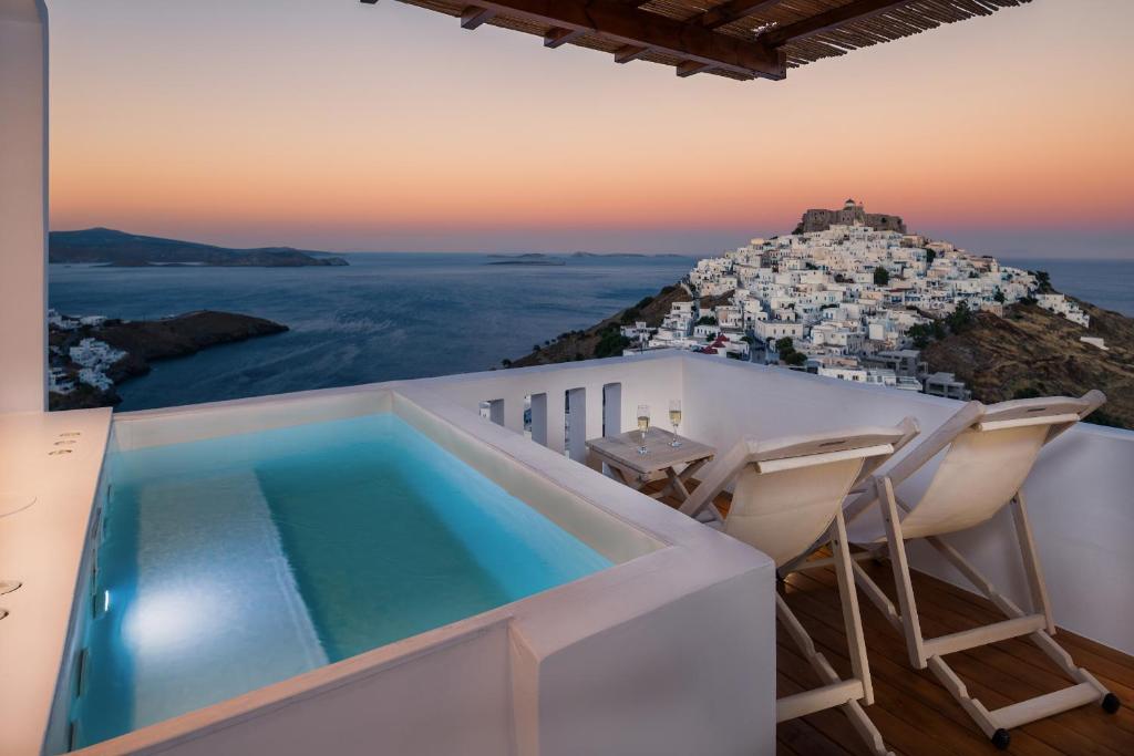 a house with a swimming pool and two chairs at Oneiro Luxury Suites-Adults Only in Astypalaia