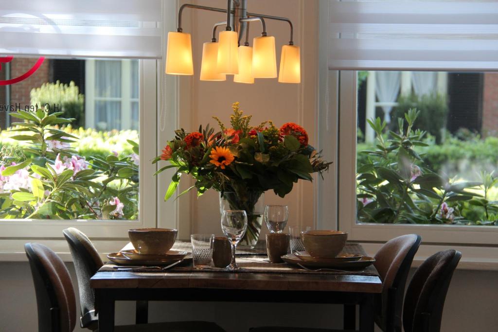 una mesa de comedor con un jarrón de flores. en B&B de Dorpsdokter en Udenhout