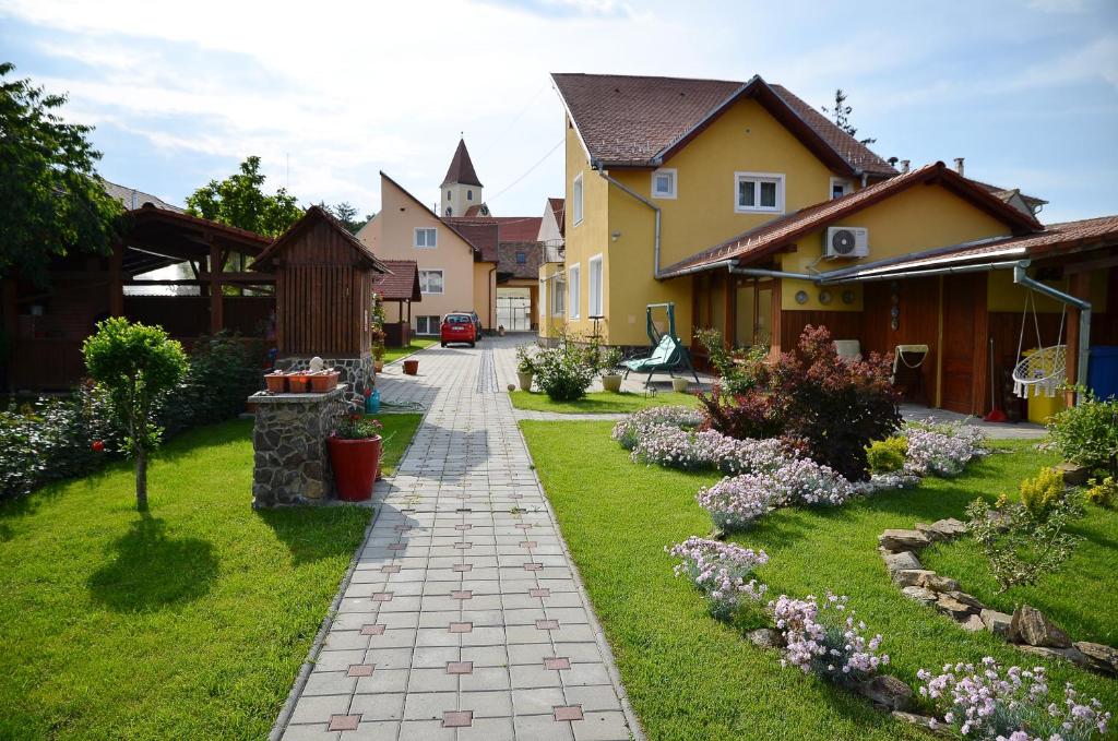 a walkway through a yard with houses and flowers at Pension Artemis in Sibiu