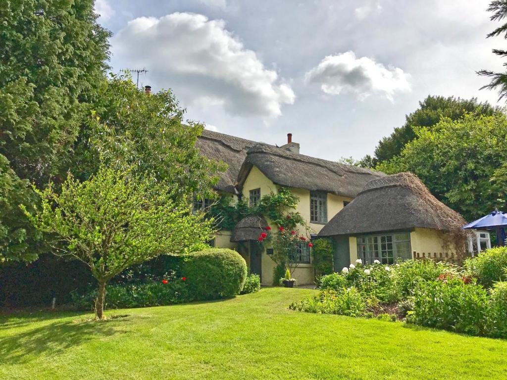 una casa con techo de paja y patio en Beck Cottage, Wood Green, New Forest UK en Breamore