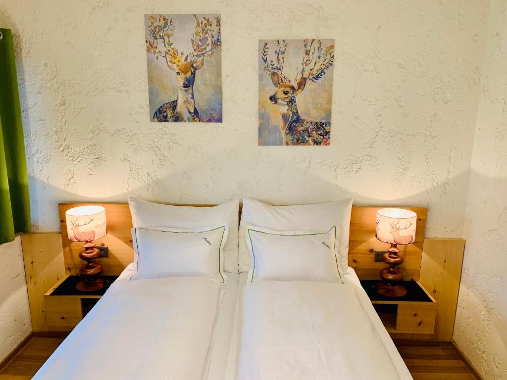 sypialnia z 2 poduszkami i 2 obrazami jelenia na ścianie w obiekcie Appartement Azalea Oetz w mieście Oetz